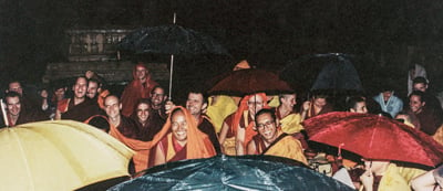 Lama Yeshe and Lama Zopa Rinpoche with Sangha and students doing puja in the rain, Bodhgaya, India, 1982.